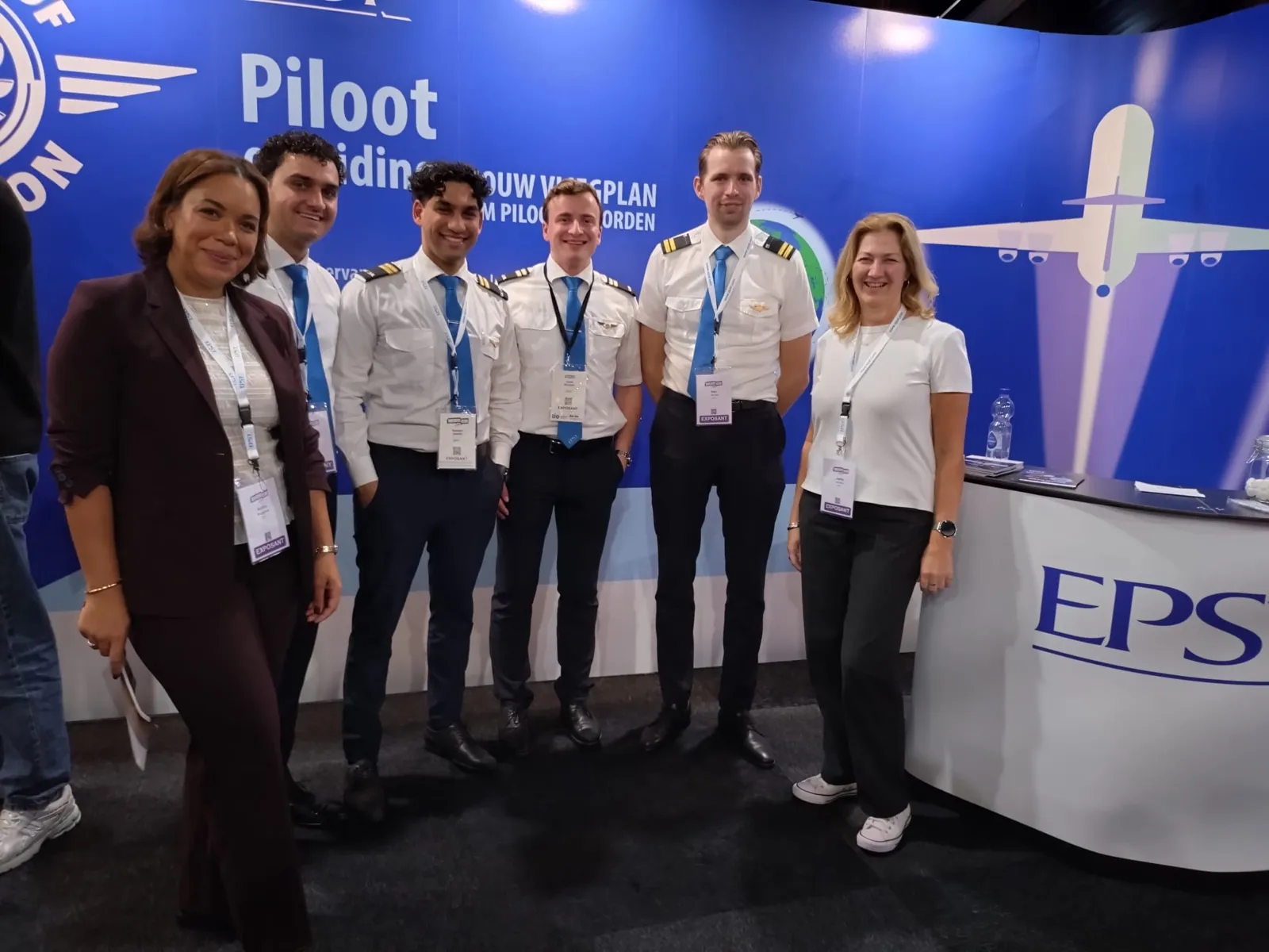 Het EPST-team met piloten in uniform bij de stand op een onderwijsbeurs