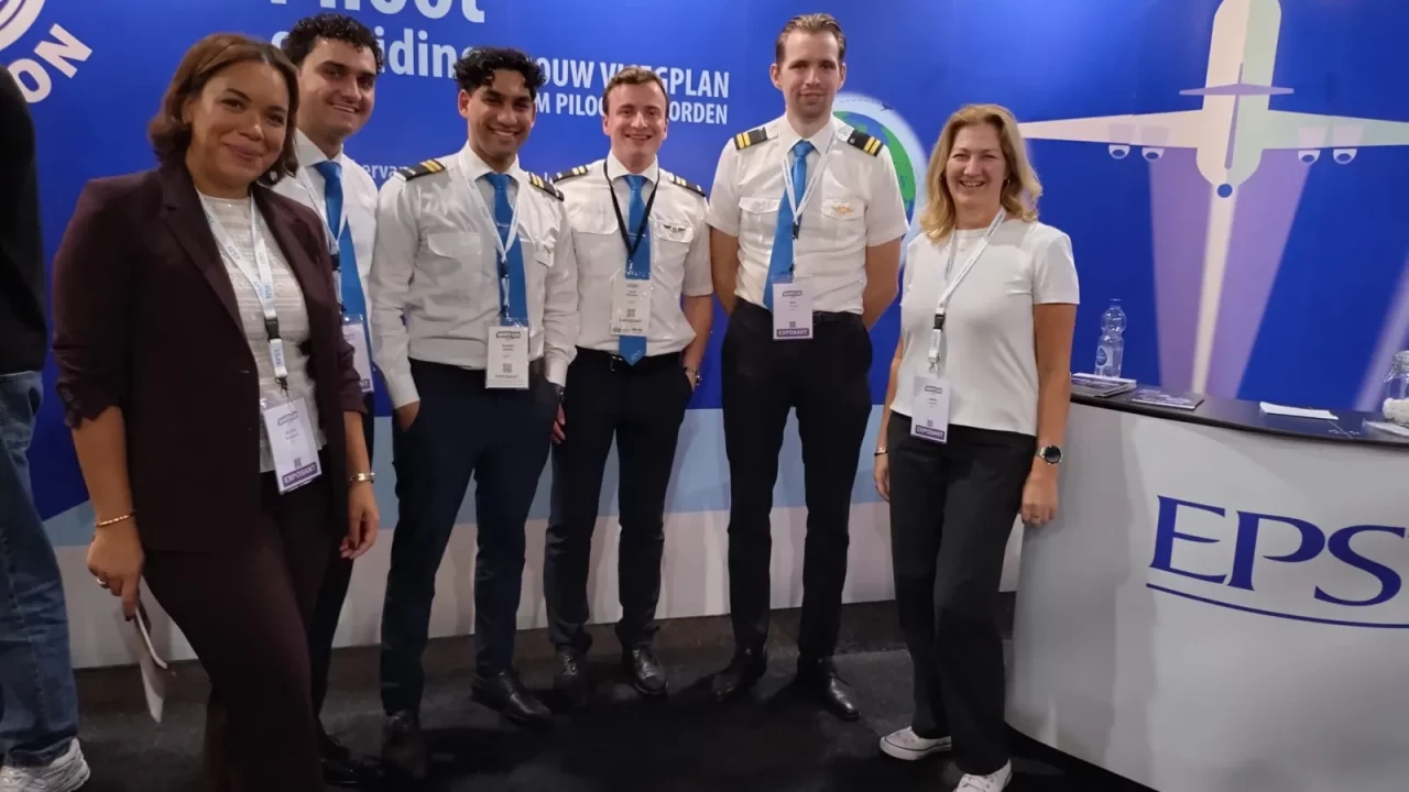 Het EPST-team met piloten in uniform bij de stand op een onderwijsbeurs